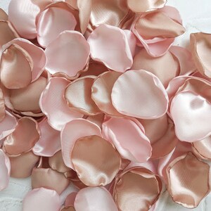May include: A collection of rose petals in shades of blush pink and rose gold. The petals are made of satin fabric and are perfect for weddings, parties, or other special occasions.