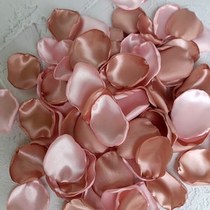 May include: A pile of rose petals in shades of pink and peach. The petals are made of satin and have a soft, silky texture.