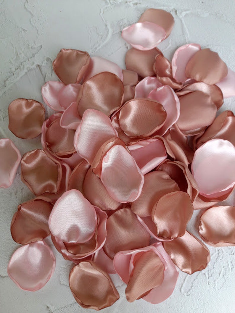 May include: A pile of rose petals in shades of pink and peach. The petals are made of satin and have a soft, silky texture.