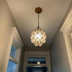 Geometric pendant light hanging in a bright hallway, creating a warm decorative focal point.