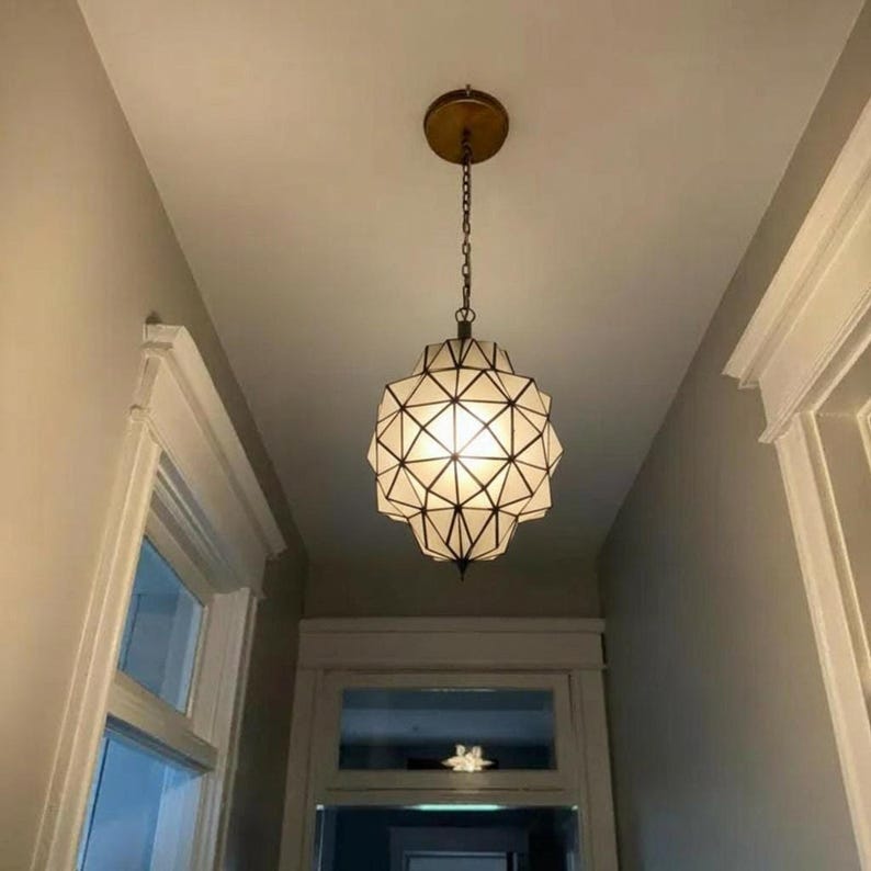 Geometric pendant light hanging in a bright hallway, creating a warm decorative focal point.