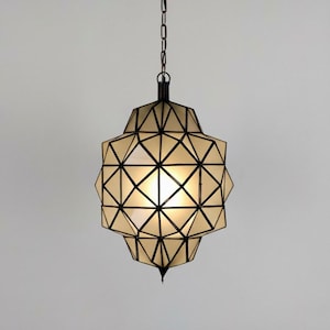 Geometric pendant lamp with intricate black metal framework and warm illuminated panels