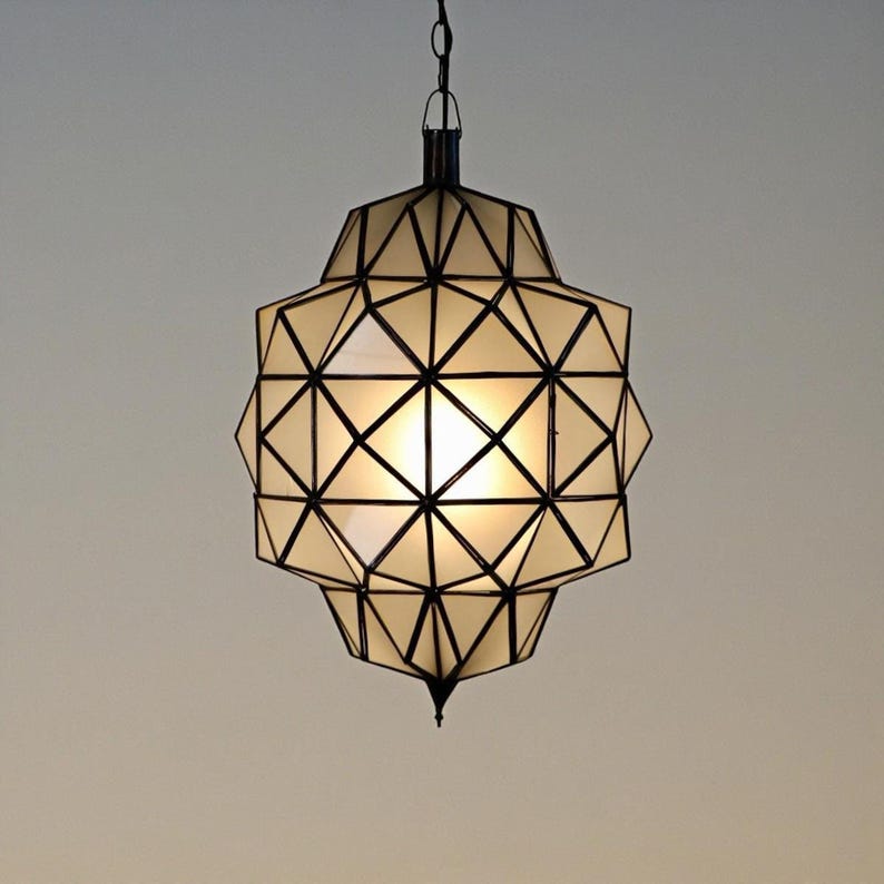 Handmade geometric pendant light with black metal framing and warm glowing panels, creating an elegant modern Moroccan-inspired design.