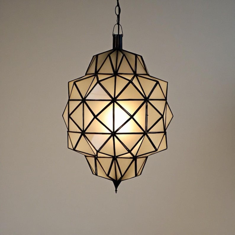 Warm glowing geometric pendant light with intricate black metal framework.