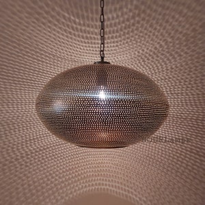 May include: A round, brass pendant light with a perforated design. The light is hanging from a chain and casts a patterned shadow on the wall.