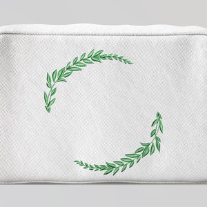 May include: White canvas makeup bag with a green embroidered wreath design.