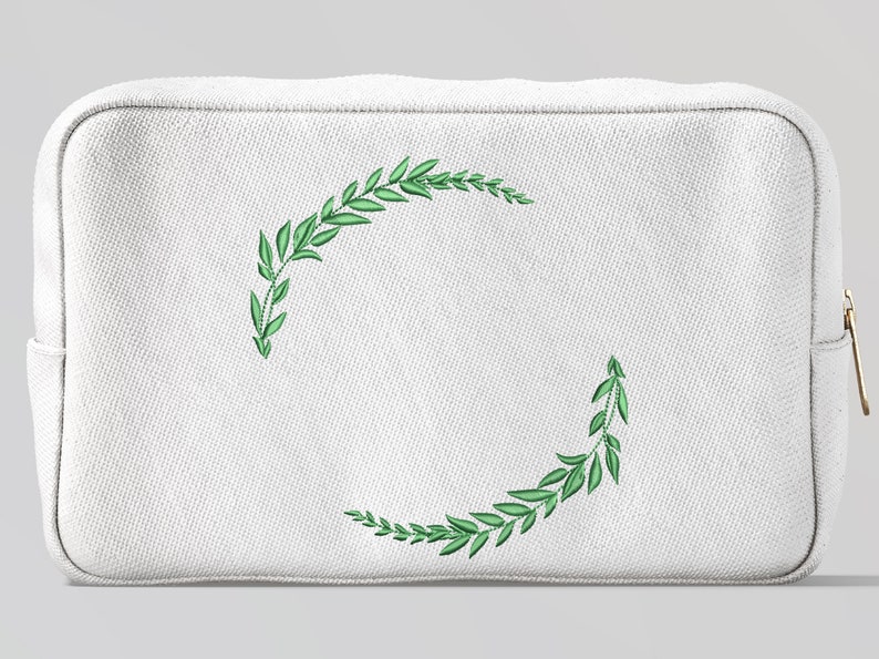 May include: White canvas makeup bag with a green embroidered wreath design.