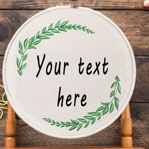 May include: A white embroidery hoop with a green leafy design and the text "Your text here".