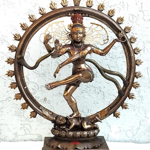 Könnte beinhalten: Bronzestatue von Shiva Nataraja, der hinduistischen Gottheit, in einer Tanzpose innerhalb eines kreisförmigen Rahmens. Die Statue weist detaillierte Merkmale auf, darunter mehrere Arme, eine Kobra und eine Figur an der Basis. Der Rahmen ist mit dekorativen Elementen verziert.