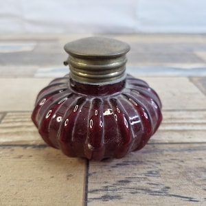 May include: A white ceramic mug with a black handle and the text "But First, Coffee" in a black, bold font. The mug is sitting on a wooden surface. The mug is approximately 4 inches tall.