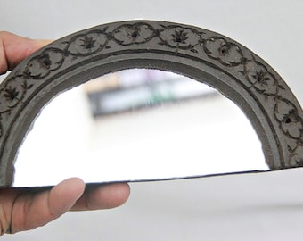 Può includere: Uno specchio a mezzo cerchio con una cornice in legno intagliata. La cornice presenta un motivo floreale ed è dipinta di colore marrone scuro.