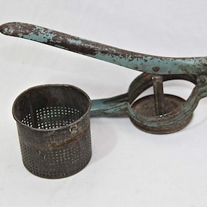 May include: A vintage blue metal potato ricer with a round, perforated container and a lever handle.