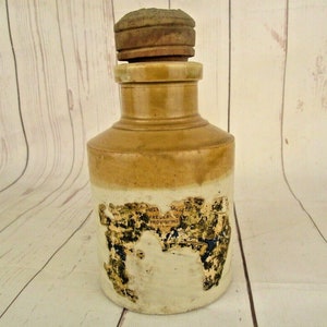 Peut inclure: Un pot en grès vintage avec un couvercle en bois. Le pot porte une étiquette sur laquelle est inscrit "Prize Jars, Frederick & Co. Provisions".