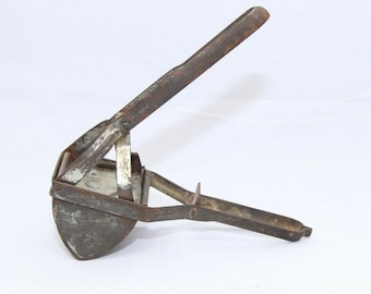 May include: An antique, rusty metal potato ricer. The kitchen utensil has a semi-circular bowl with a series of small holes, a hinged design, and long handles for pressing. The ricer is designed to mash cooked potatoes.
