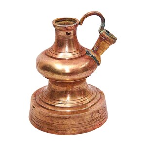 May include: A copper pitcher with a rounded body and a spout. The pitcher has a handle and a wide base.