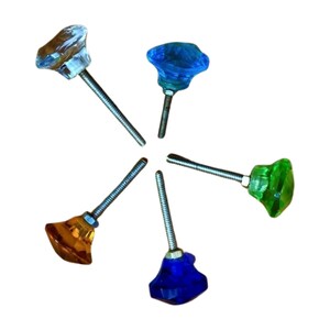 May include: Five colorful glass cabinet knobs with metal screws. The knobs are in shades of blue, green, orange, and clear.