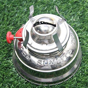 May include: A silver metal camping stove with a red knob and the words "Sunlite" and "P.H.D." printed on the side.
