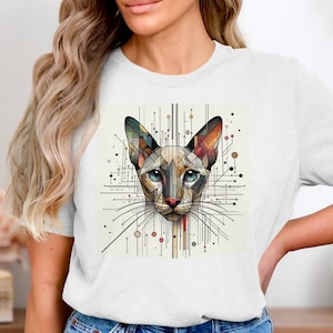 May include: A white t-shirt with a geometric design of a cat's face in shades of blue, orange, yellow, and brown. The design is surrounded by lines and dots.
