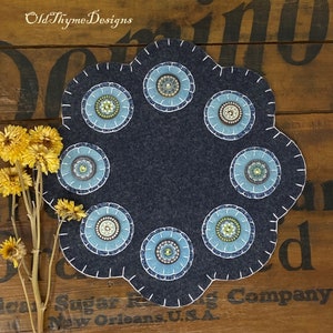 May include: A blue felt table runner with a scalloped edge and seven embroidered circles with blue, white, and green beads. The runner is on a wooden surface with the text "Old Thyme Designs" in the top left corner.