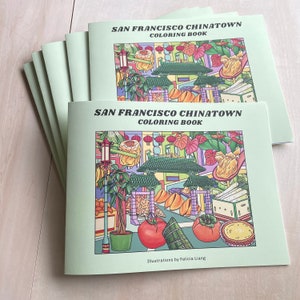 Peut inclure: Une pile de livres &agrave; colorier avec une couverture verte illustrant des sc&egrave;nes de Chinatown &agrave; San Francisco. La couverture pr&eacute;sente une illustration color&eacute;e d'une rue avec des b&acirc;timents, des lanternes et de la nourriture. Le titre "San Francisco Chinatown Coloring Book" est imprim&eacute; en lettres noires en gras sur la couverture. Le texte "Illustrations by Felicia Liang" est imprim&eacute; en lettres noires en bas de la couverture.