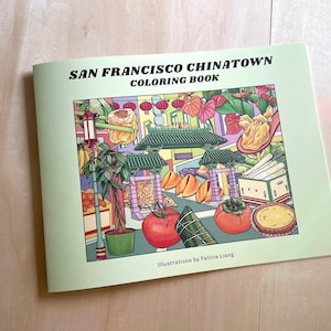 Peut inclure: Un livre de coloriage vert avec le titre "San Francisco Chinatown Coloring Book" et des illustrations d'une sc&egrave;ne de rue de Chinatown avec des lanternes, de la nourriture et des plantes. Le livre est de Felicia Liang.