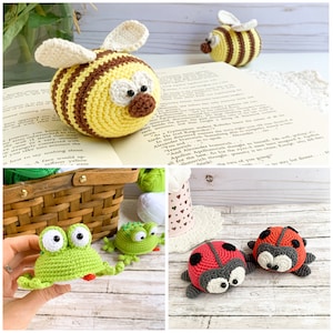 May include: A selection of handmade crochet toys, featuring a yellow and brown bee, a green frog, and two red ladybirds with black spots. The toys are displayed on a white surface with a book and basket.