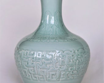 Exclusivo jarrón de porcelana celadón azulado con motivos de dragones tallados en el esmalte y con la marca Qianlong (1736-1796) moldeada en la base.