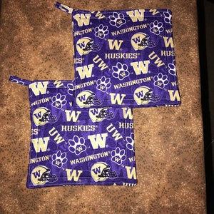 May include: Two purple and gold pot holders with the University of Washington Huskies logo and the words "UW Huskies" and "Washington" repeated on them.