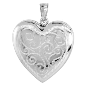 Puede incluir: Un colgante plateado en forma de corazón pulido con un intrincado diseño de filigrana en espiral. El colgante tiene una argolla en la parte superior para una cadena. El corazón es liso y reflectante, con un patrón detallado en su superficie.
