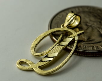 May include: A gold-colored initial 'D' pendant charm, with a diamond-cut design, next to a US quarter dollar coin.