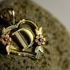 Colgante con dije de flor y letra inicial en forma de corazón en oro amarillo y rosa de 10 quilates en dos tonos