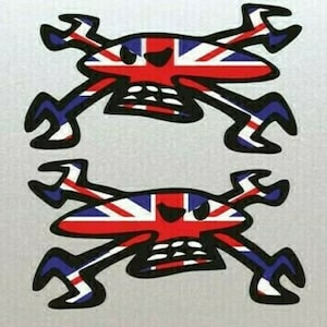 以下が含まれることがあります： 赤、白、青のユニオンジャックの旗のデザインが施された、黒と白のドクロとクロスボーンのステッカー2枚