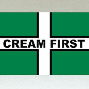 Pode incluir: Uma bandeira verde e branca com uma borda preta e o texto "CREAM FIRST" em preto.