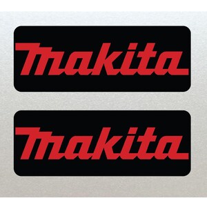 Puede incluir: Dos pegatinas rectangulares negras con la palabra "Makita" en letras rojas.