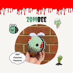 Pode incluir: Um padrão de crochê para um brinquedo amigurumi de abelha zumbi verde e preto. O padrão está disponível para download em PDF. A imagem mostra o brinquedo terminado sendo segurado em uma mão.