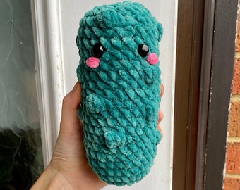 May include: A green crocheted plush toy shaped like a bacterium with black eyes and pink cheeks.