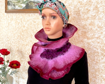 May include: A pink and purple felted wool neck warmer with a ruffled edge. The neck warmer is worn by a mannequin with a patterned headband.