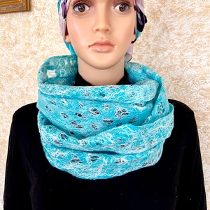 May include: A turquoise blue lace infinity scarf with a white lace pattern. The scarf is worn by a mannequin with a floral patterned head scarf.