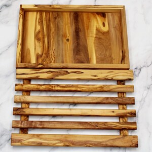 Puede incluir: Una bandeja de servir de madera con una base de listones. La bandeja est&aacute; hecha de madera de olivo y tiene un acabado natural. La bandeja es perfecta para servir aperitivos, entrantes o postres.
