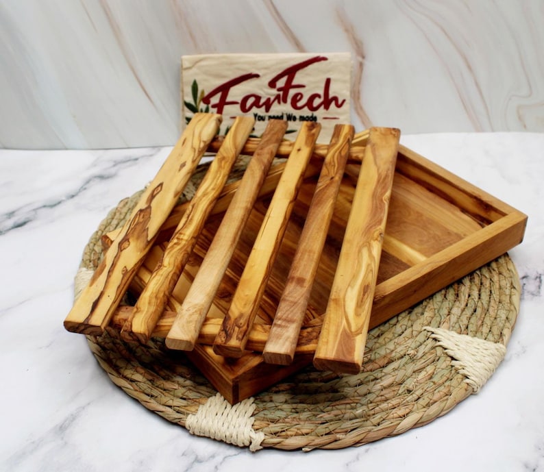 Puede incluir: Una bandeja de servir de madera con un dise&ntilde;o de listones. La bandeja est&aacute; hecha de madera de olivo y tiene un acabado natural. La bandeja es perfecta para servir pan, queso u otros aperitivos.