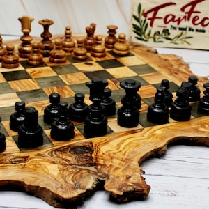 May include: A wooden chess set with black and brown pieces on a checkered board. The board is made of olive wood and has a unique, organic shape. A wooden sign with the text "Fantech" is in the background.