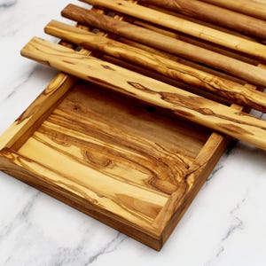 Puede incluir: Una bandeja de servir de madera con un dise&ntilde;o de listones. La bandeja est&aacute; hecha de madera de olivo y tiene un acabado natural. La bandeja es perfecta para servir aperitivos, aperitivos o queso.
