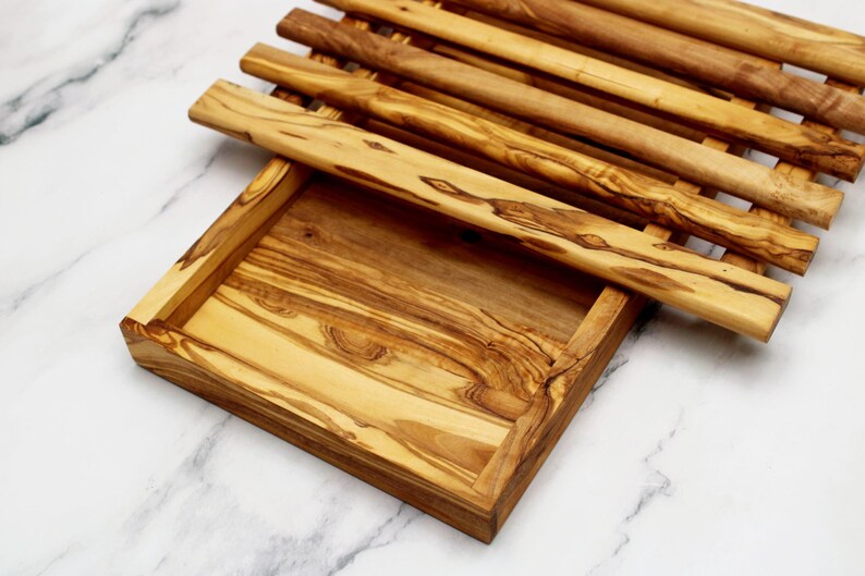 Puede incluir: Una bandeja de servir de madera con un dise&ntilde;o de listones. La bandeja est&aacute; hecha de madera de olivo y tiene un acabado natural. La bandeja es perfecta para servir aperitivos, aperitivos o queso.