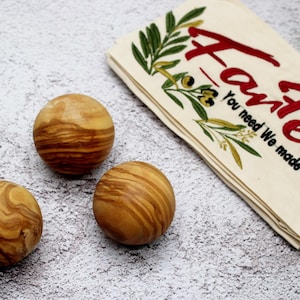 Könnte beinhalten: Drei Holzbälle mit natürlicher Holzmaserung. Die Bälle sind rund und haben eine glatte Oberfläche. Die Bälle liegen auf einem hellgrauen Hintergrund.