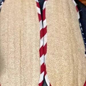 May include: Two loofah bath scrubbers with a natural beige texture. Each scrubber is bordered with red and white striped fabric, and a blue fabric with white stars. The scrubbers are designed for use in the bath or shower.