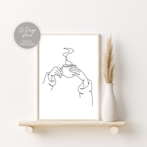 May include: Line art drawing of a hand holding a steaming cup of coffee or tea. The drawing is in black and white and is on a white background.