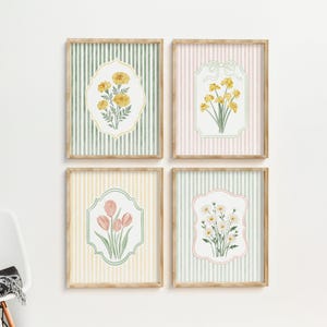 May include: Four framed floral art prints. Each print features a different flower illustration in a decorative frame against a striped background. The frames are light brown, and the backgrounds are pastel colors: green, pink, and yellow.