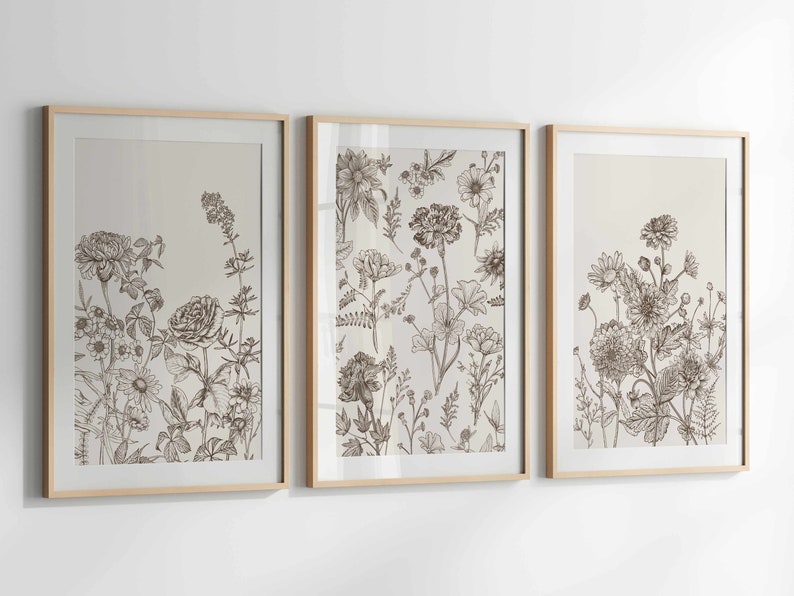 May include: Three framed botanical art prints. Each print features detailed line drawings of various flowers and foliage in shades of brown and beige. The frames are light wood.