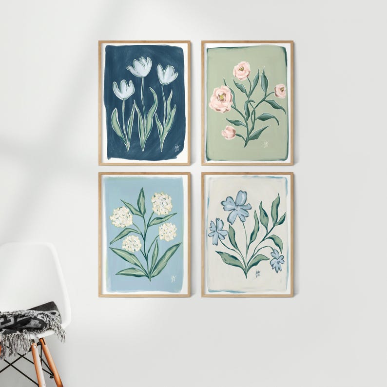 May include: Four framed floral art prints. Each print features a different flower design in a soft color palette. The top left print has white tulips on a navy background. The top right print has pink flowers on a green background.