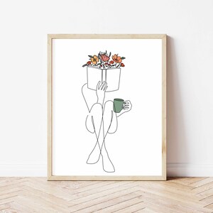 May include: Line art drawing of a person sitting with a book and a cup of coffee. The book is open and has flowers on top of it. The person is sitting with their legs crossed and holding the cup in their right hand.